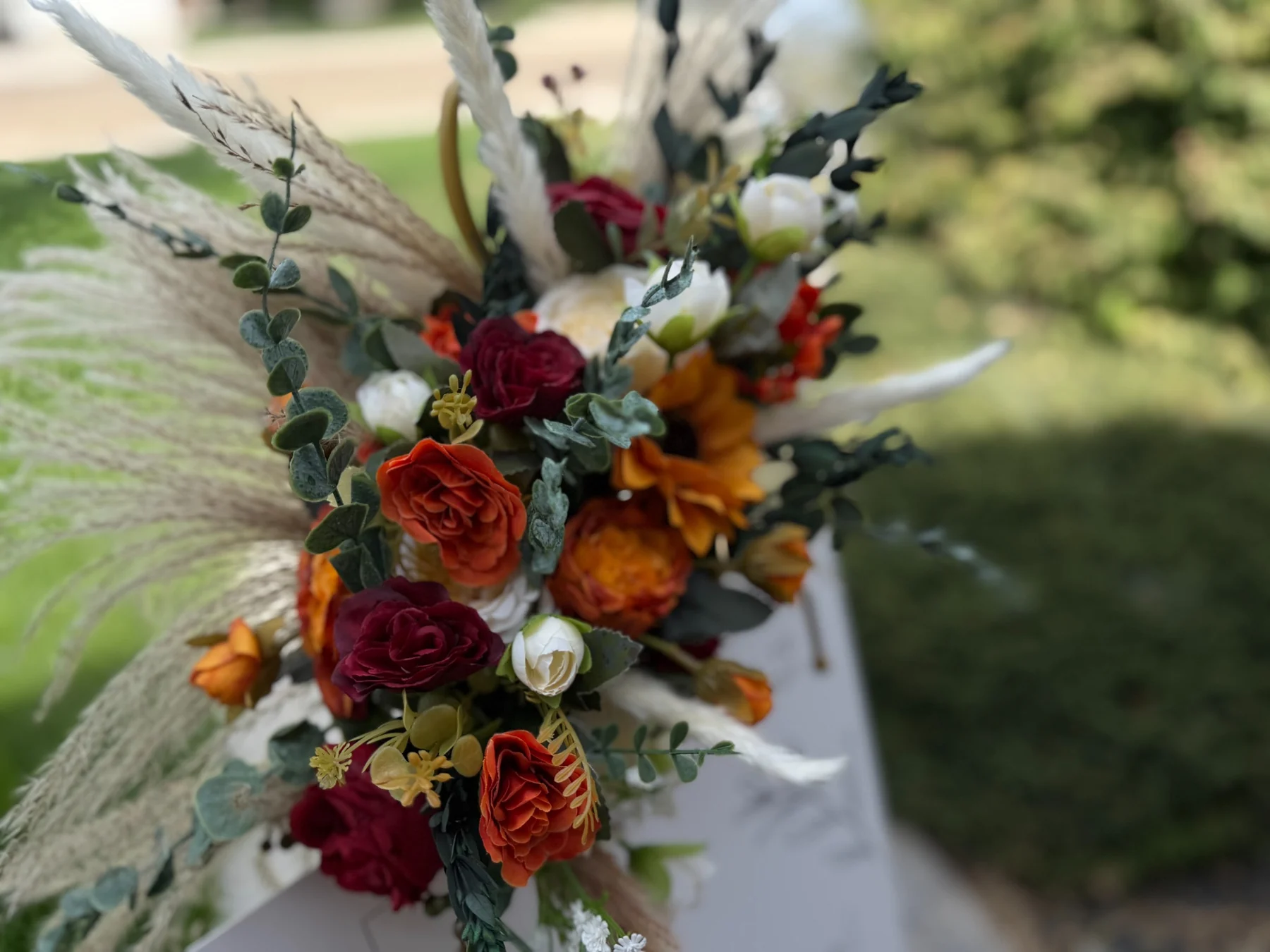 Close-up of orange burgundy and ivory floral styling on the easel