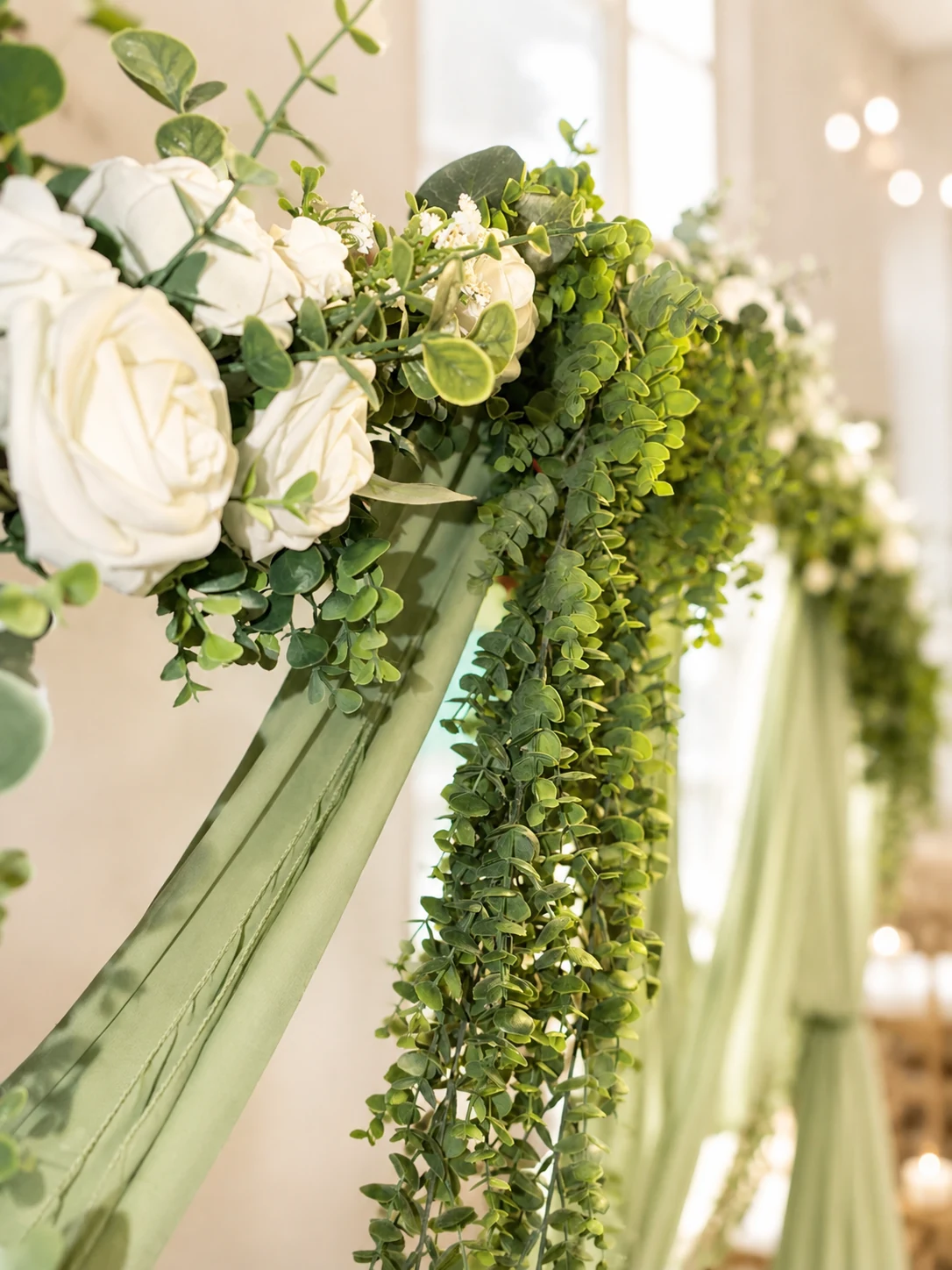 Close-up of white florals and greenery on sage draping indoors