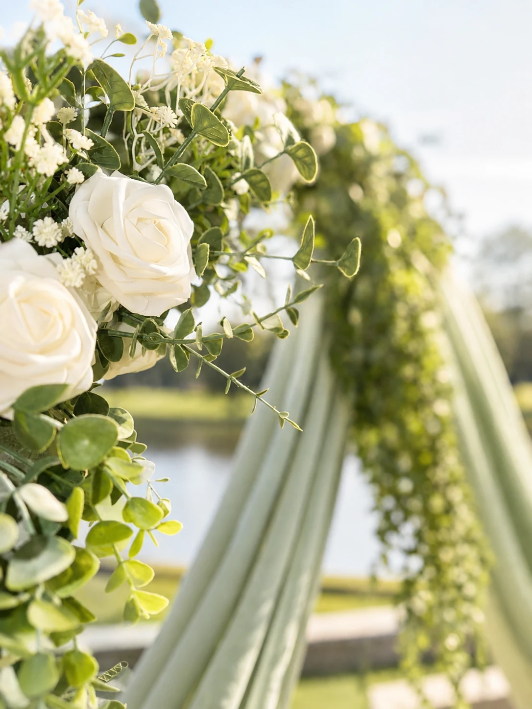 Outdoor close-up of white florals and greenery on the round arch