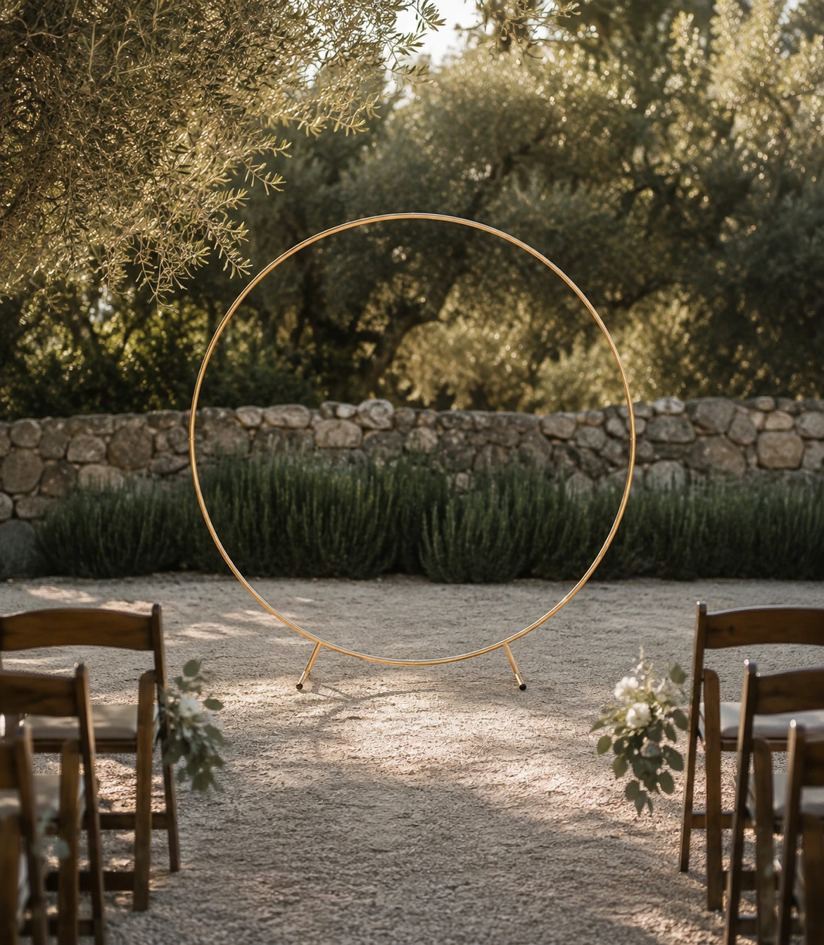 Bare gold round ceremony arch framed by wedding aisle chairs